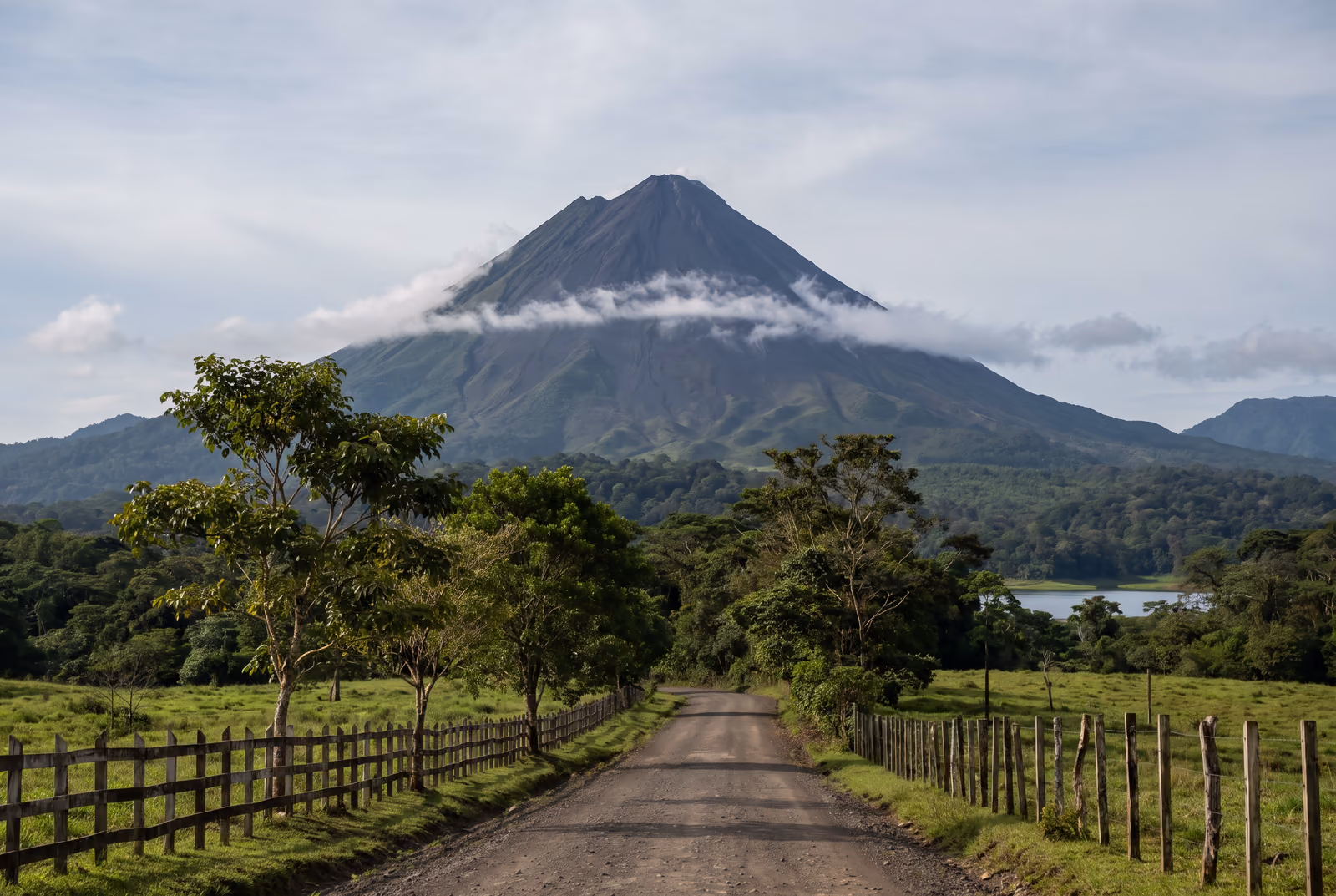 Vulkan Arenal mit Wolkenhaube über Weiden und Wald bei La Fortuna