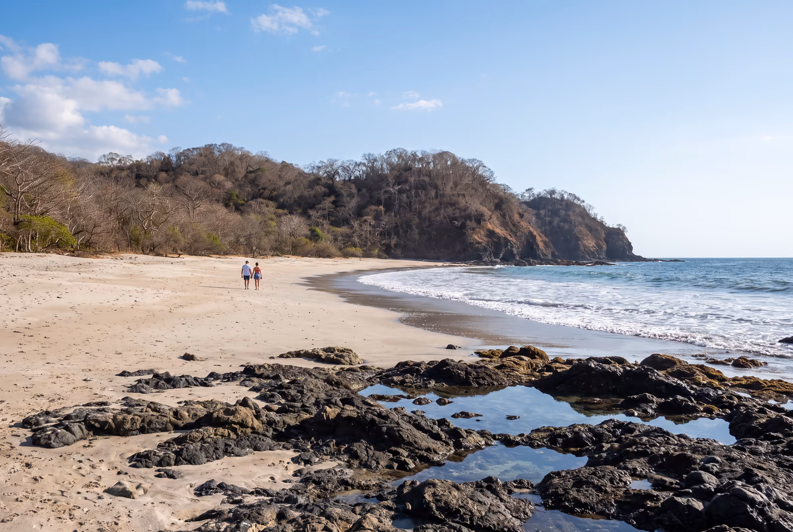 Heller Sandstrand und Vulkanfelsen auf der Halbinsel Nicoya, Trockenwald auf der Landzunge