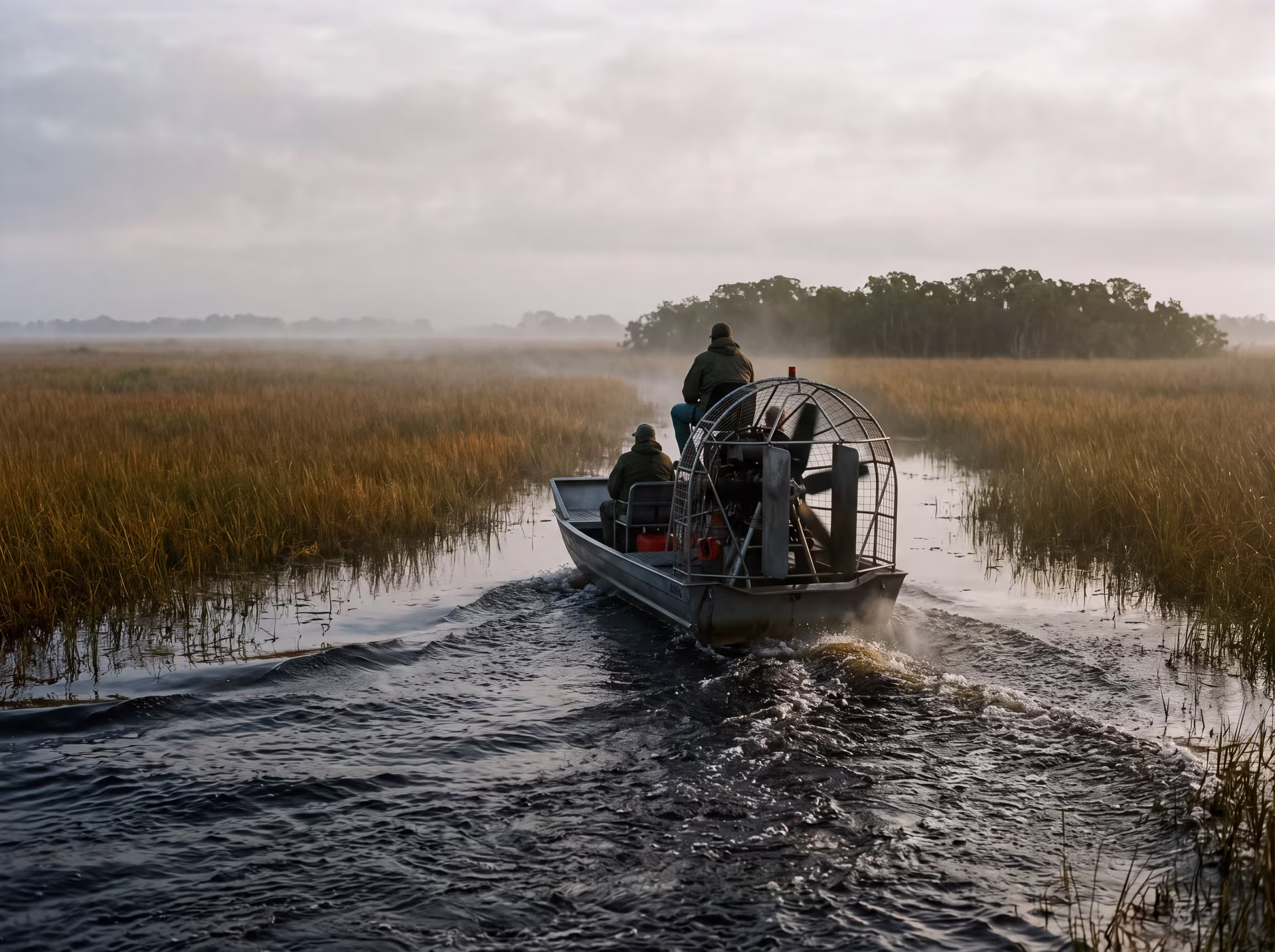 Airboat crossing the Everglades marshes between tall grasses and morning mist
