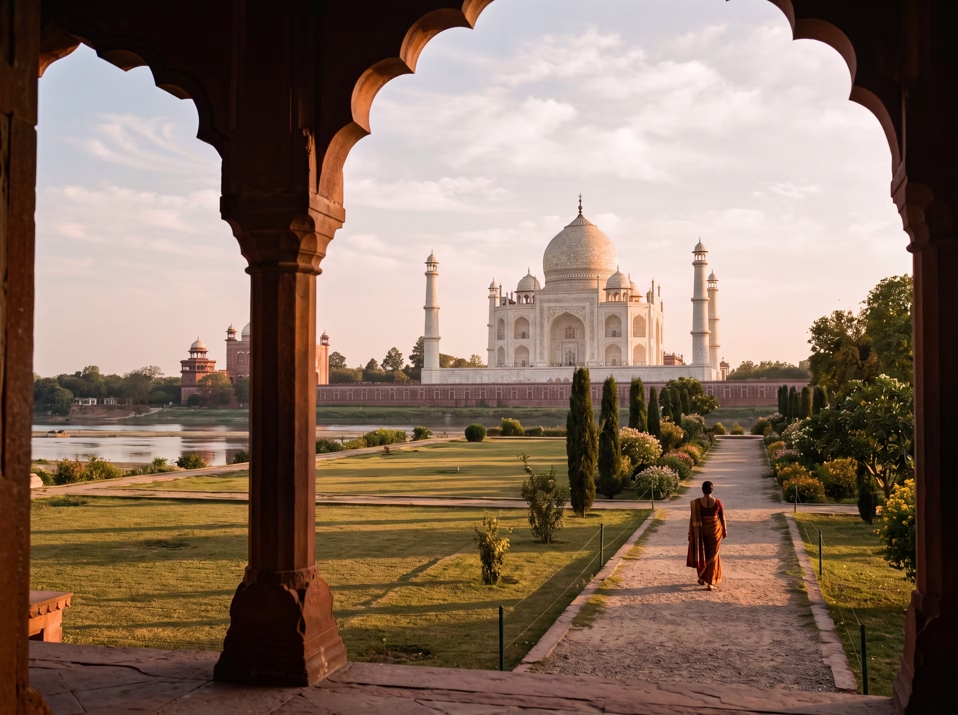 The marble of the Taj Mahal tinged gold and rose at sunset, a silhouette beneath an archway