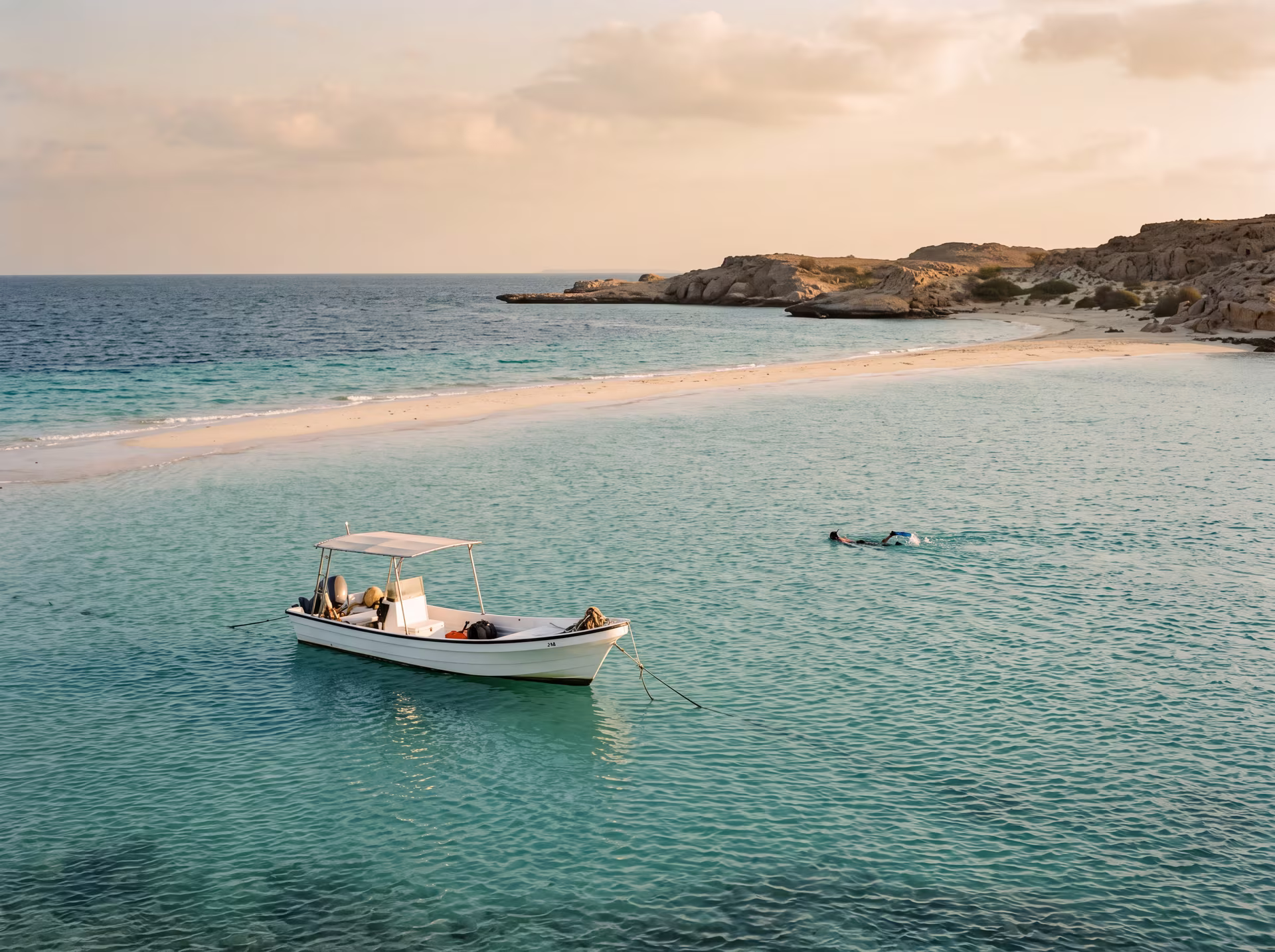 Eaux turquoise et sable clair des îles Dimaniyat, bateau mouillant près du récif