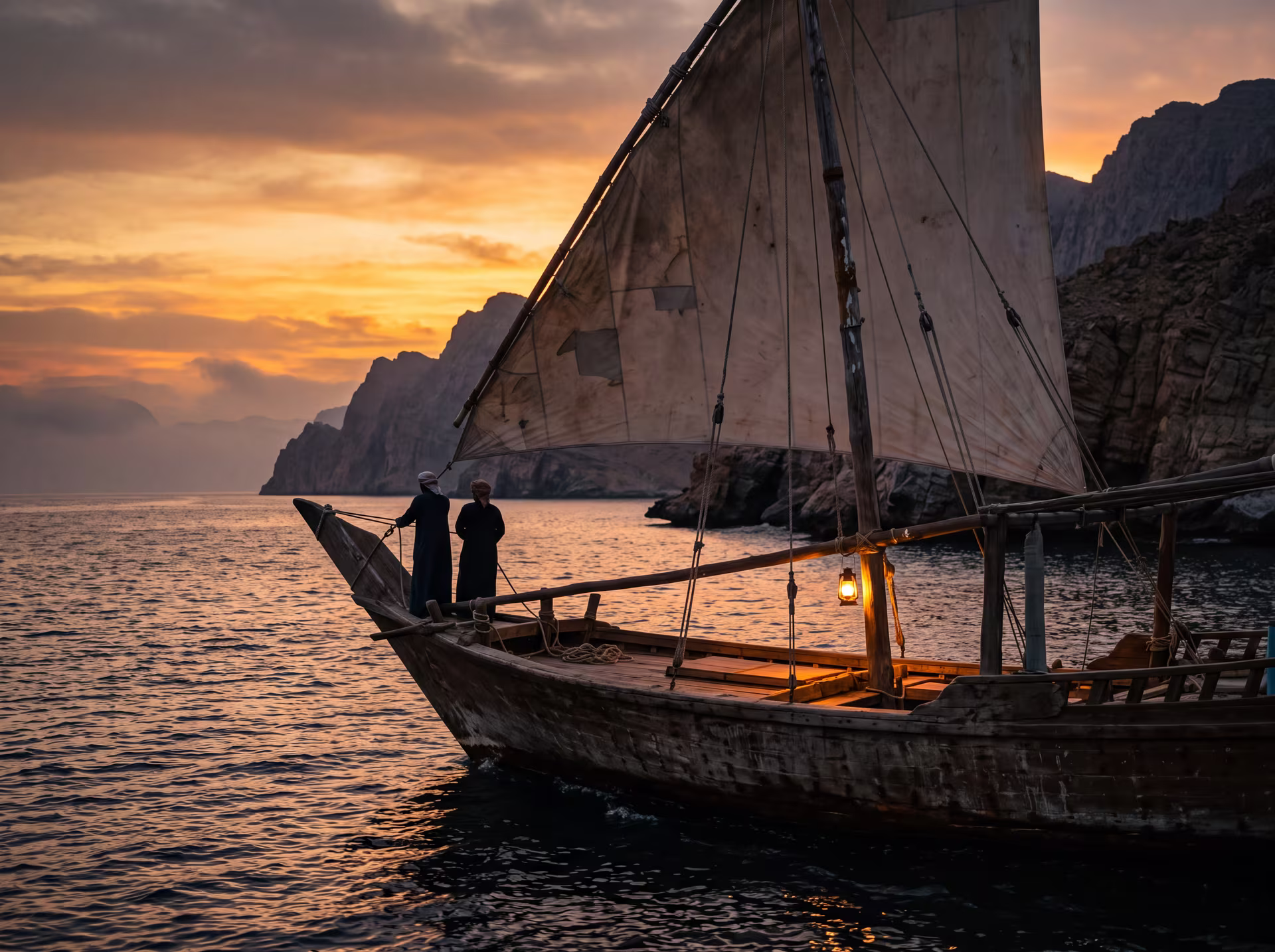 Boutre traditionnel voguant au coucher du soleil sur le golfe d'Oman, falaises en arrière-plan