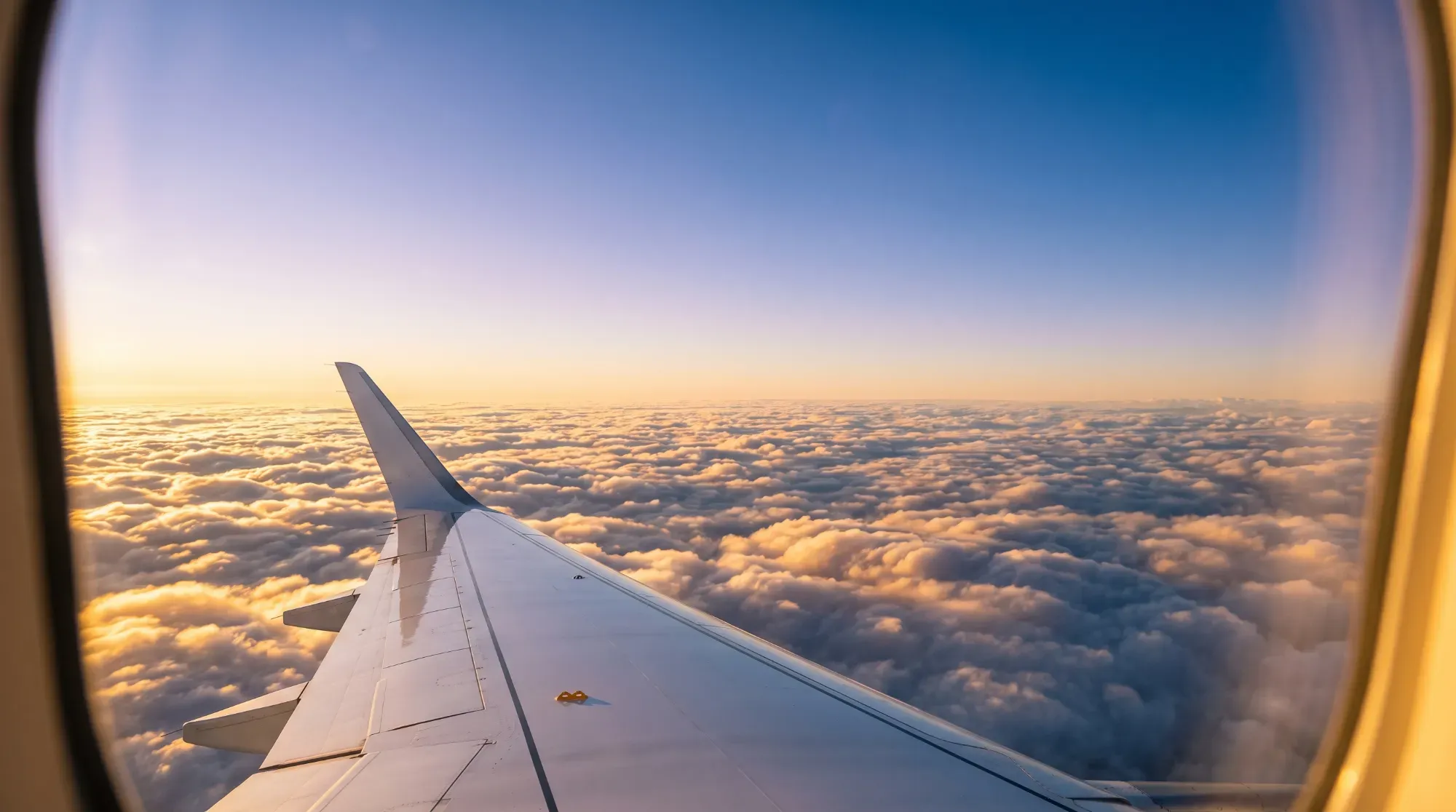 Vue depuis le hublot d'un avion au coucher du soleil, illustrant la recherche du meilleur vol pour un voyage sur mesure